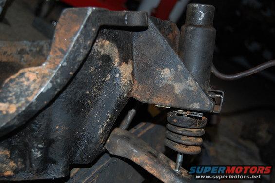 Rusty metal suspension part with a coiled spring, close-up view