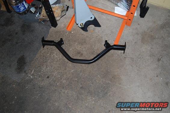 Black metal V-shaped bar with two mounting plates, on concrete floor