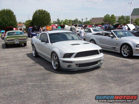 Silver Ford Mustang with hood scoops and black grille, parked in a lot