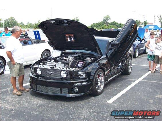 Black 2007 Ford Mustang with hood and doors open, parked at a car show
