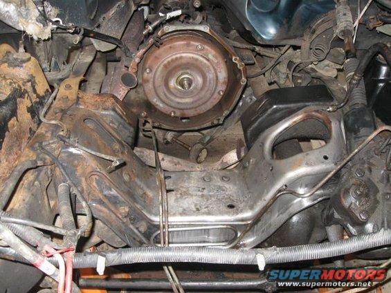 underneath view of vehicle transmission and frame components, some rust visible