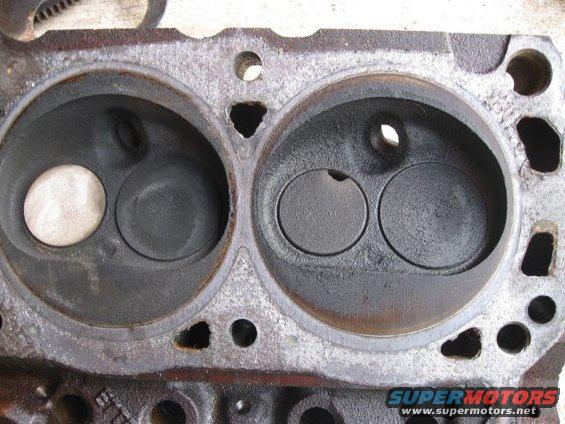 Engine cylinder head with two combustion chambers, one with a clean valve and one with carbon buildup