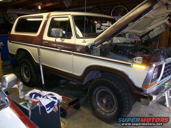 1979 Ford Bronco in garage, hood open, showing engine bay. Two-tone paint with brown trim