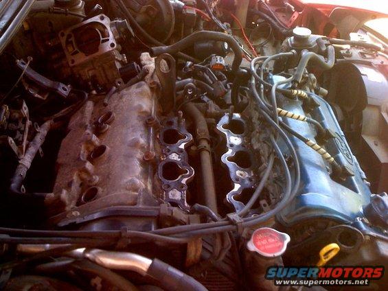 Engine bay with intake manifold removed, showing cylinder heads and wiring
