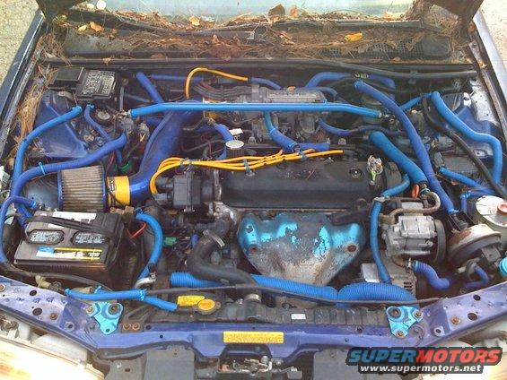 engine bay with blue hoses and wires, leaves in windshield area