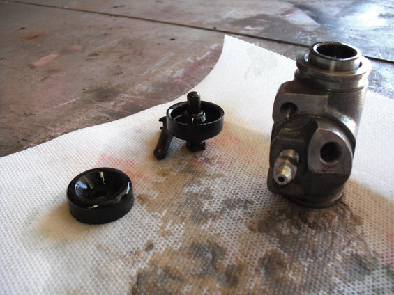 Brake master cylinder body, piston, and rubber seal on paper towels