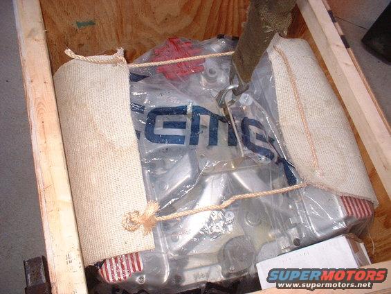 Engine wrapped in plastic inside a wooden crate, with burlap padding and straps