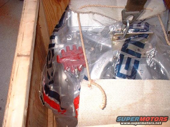 Engine part in crate with red component and blue lettering