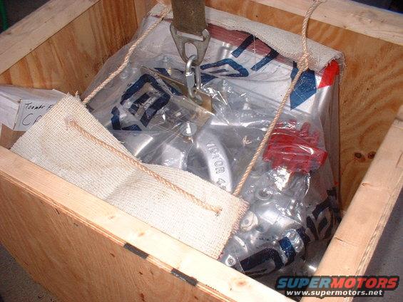Engine part in plastic wrap inside a wooden crate. Text on part reads '1970R 4'