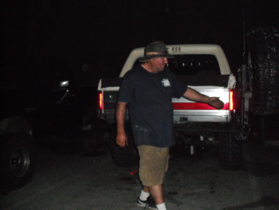 1991 Ford Bronco rear, white with red stripe, spare tire mounted on back, man in hat and dark shirt