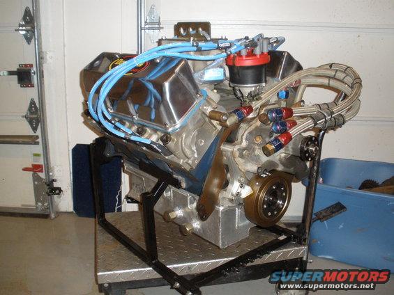 V8 engine with chrome valve covers and blue spark plug wires on a stand