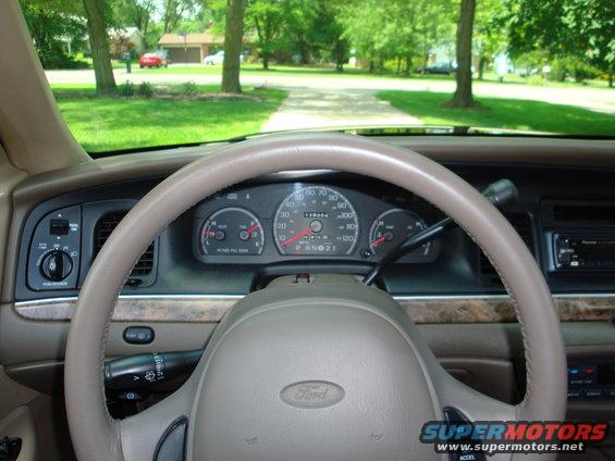 Car interior with tan steering wheel and dashboard, showing instrument cluster and radio