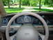 1999 Ford Crown Victoria - The dashboard of a car, viewed from the driver's seat, with a view of the road ahead through the windshield.