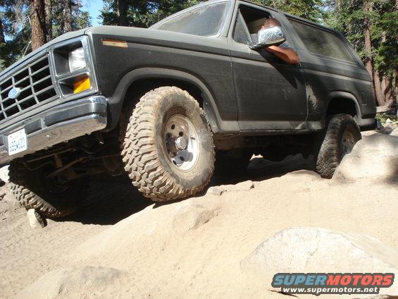 Dark gray Ford Bronco climbing rocks, front grille visible