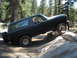 1984 Ford Bronco - A dark-colored Ford Bronco navigates a rocky obstacle on an off-road trail.