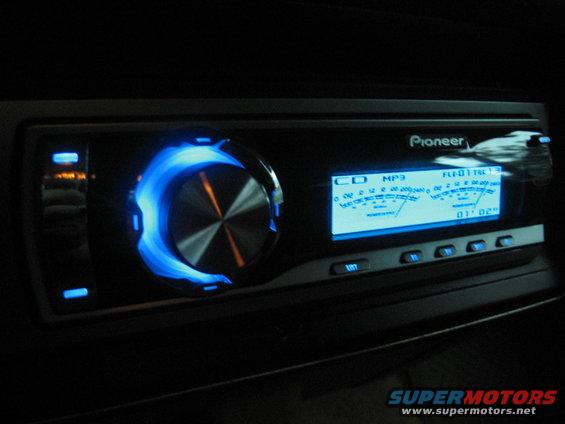 Pioneer car stereo with blue illuminated ring and digital display showing MP3 information