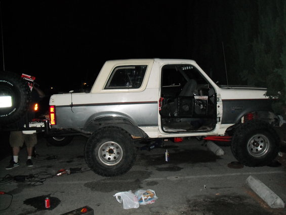 White and silver Ford Bronco with doors removed, lifted on large tires