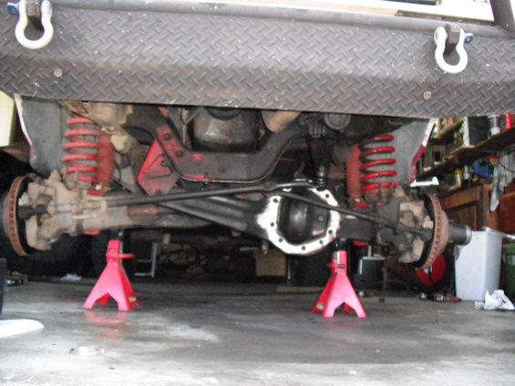 Undercarriage view of a vehicle's front axle and suspension on jack stands