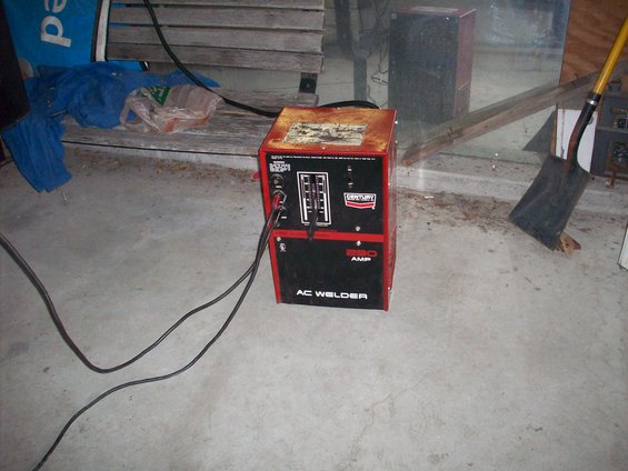 Red and black AC welder with 'CENTURY 220 AMP' visible