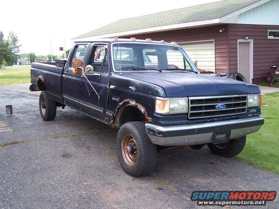 Dark blue 1990 Ford F-350 crew cab pickup truck with rust damage on fenders and mirrors