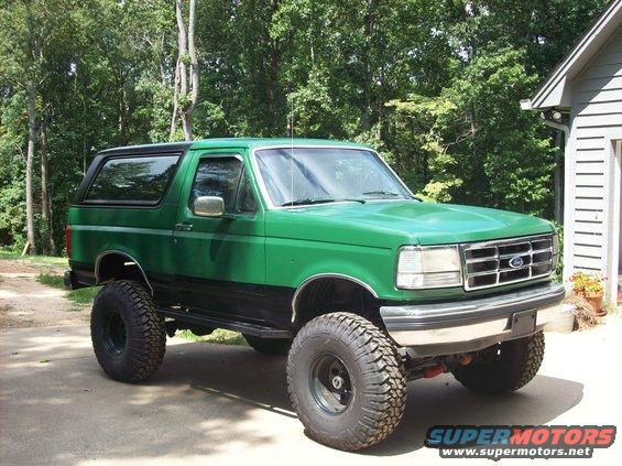Green 1992 Ford Bronco with black trim and large off-road tires, parked on a concrete driveway