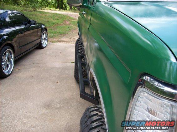 Green 1992 Ford Bronco side view with aftermarket steps and large tires