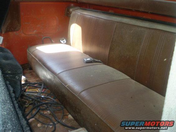 Interior view of a vehicle showing a brown bench seat and a tangle of black wires on the floor