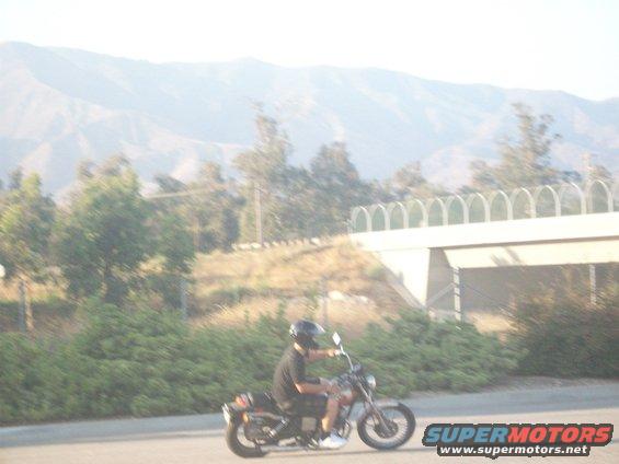 Motorcycle with rider in black shirt and helmet, seen from the side