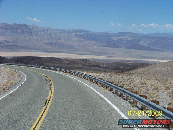 Winding asphalt road with guardrail in a desert landscape under a clear blue sky