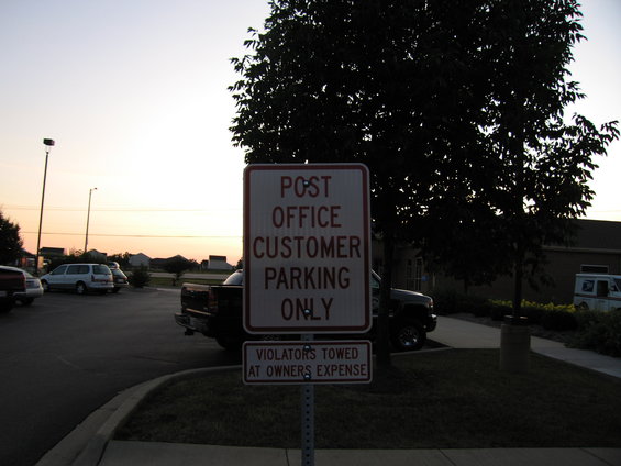 Post office customer parking sign with violator towing notice