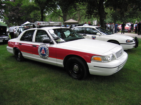 White and red police car with light bar, 3/4 front view