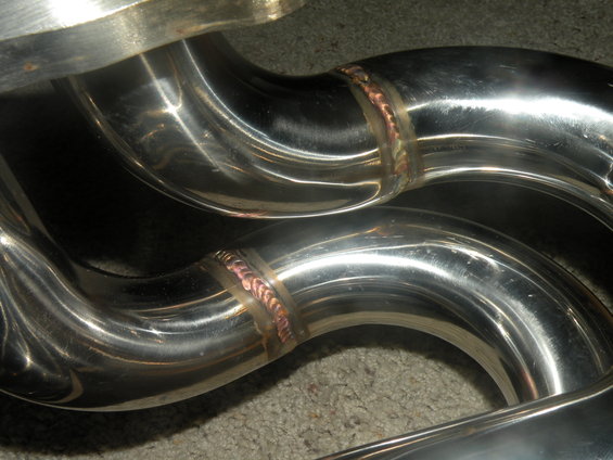 Close-up of shiny exhaust manifold pipes with visible welds