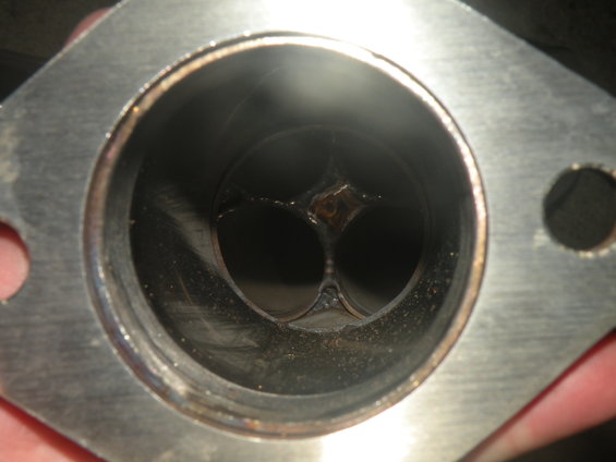 Exhaust valve with carbon buildup and slight damage, viewed from the intake side