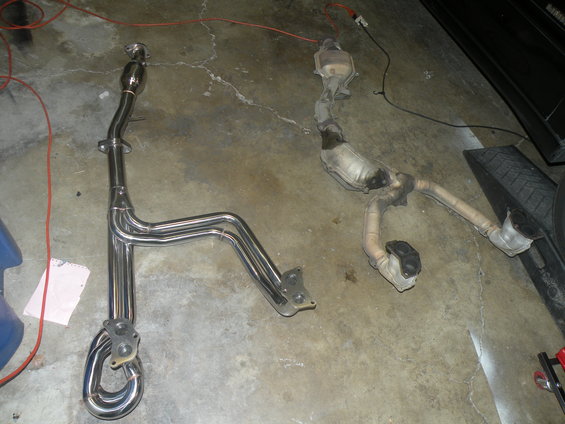 New chrome exhaust manifold and used catalytic converter assembly on concrete floor