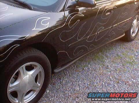 Side view of a black car with white flame decals. It has silver wheels and a side skirt