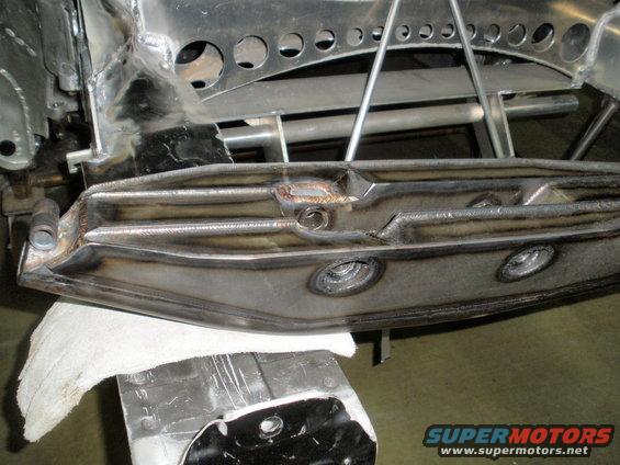 Close-up of welded metal suspension part on a stand, with a white cloth underneath