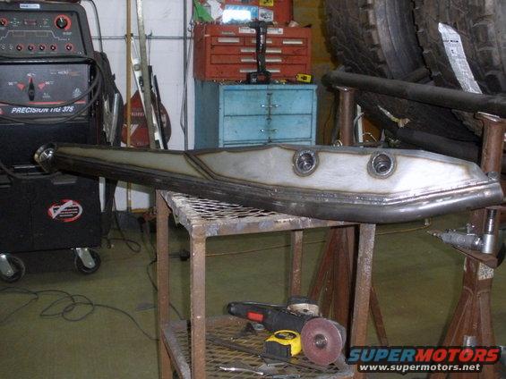 welded metal part on a workbench with a welder and grinder nearby