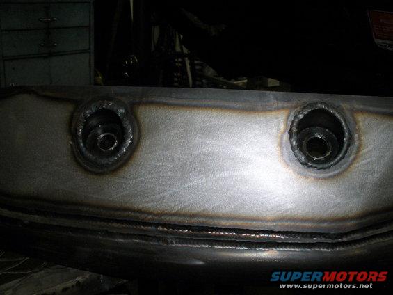 Welded metal part with two bolt holes, showing weld marks and metal sheen