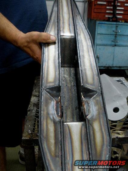 Custom fabricated metal part with visible welds, held by a person's hand