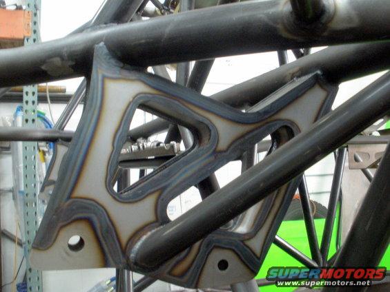 Custom suspension bracket with intricate cutouts and visible welds