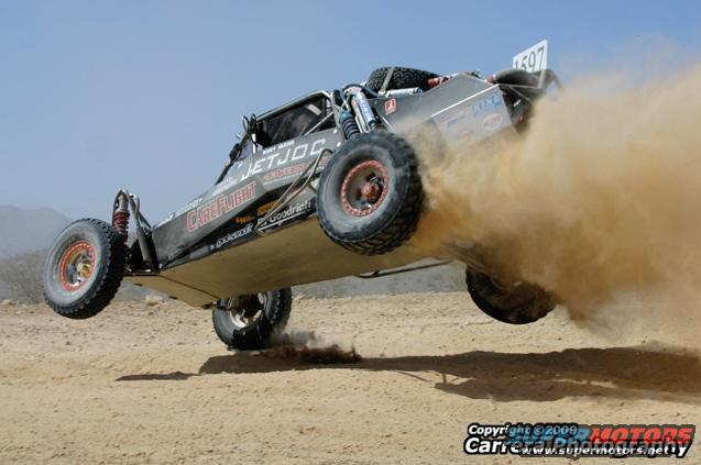 Off-road buggy mid-air, kicking up dust. Number 507 visible