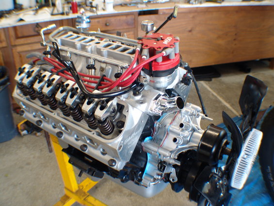 Aluminum V8 engine with red MSD distributor and chrome valve covers on a yellow stand