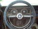 1966 Ford Ranchero - The interior of a car shows a worn dashboard with a steering wheel and two circular gauges.