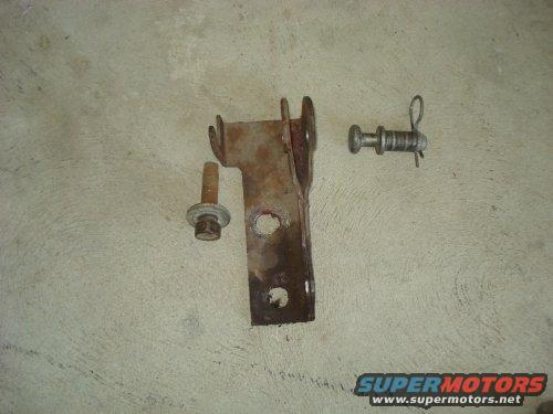Rusted metal bracket with two bolts and a cotter pin on a concrete surface