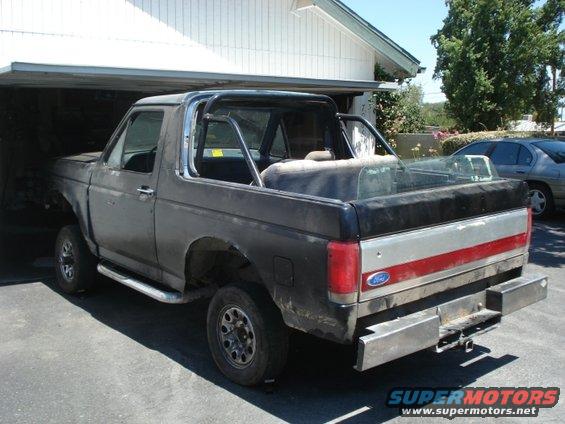 Ford Bronco parked in a garage, top removed, roll cage installed