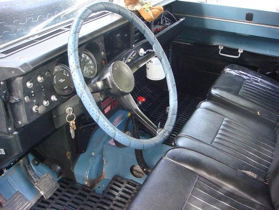 1972 Land Rover Land Rover interior with blue steering wheel cover, black seats, and dashboard gauges