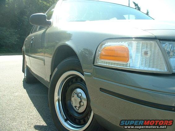 Gray 2000 Ford Crown Victoria front quarter panel and wheel, with chrome trim and black steel wheel