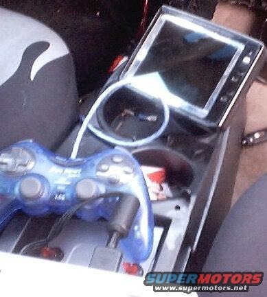 Car interior with a blue video game controller and a screen mounted on the center console