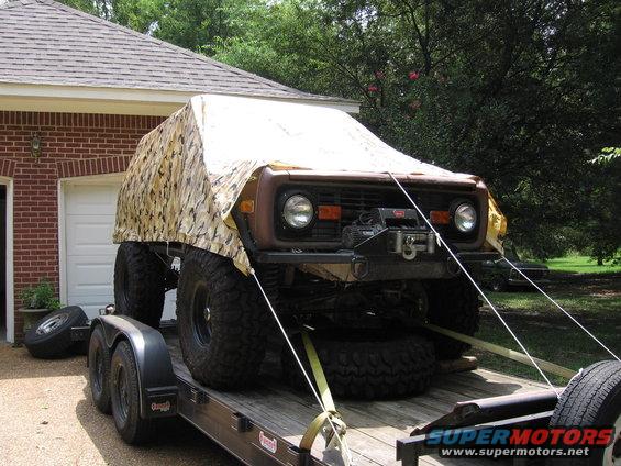 Front view of a 1974 Ford Bronco on a trailer, partially covered