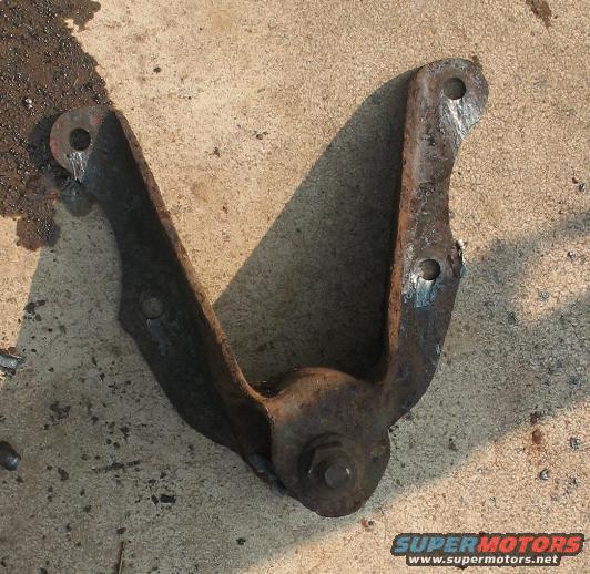 rusted metal suspension part with bolt in center, on concrete